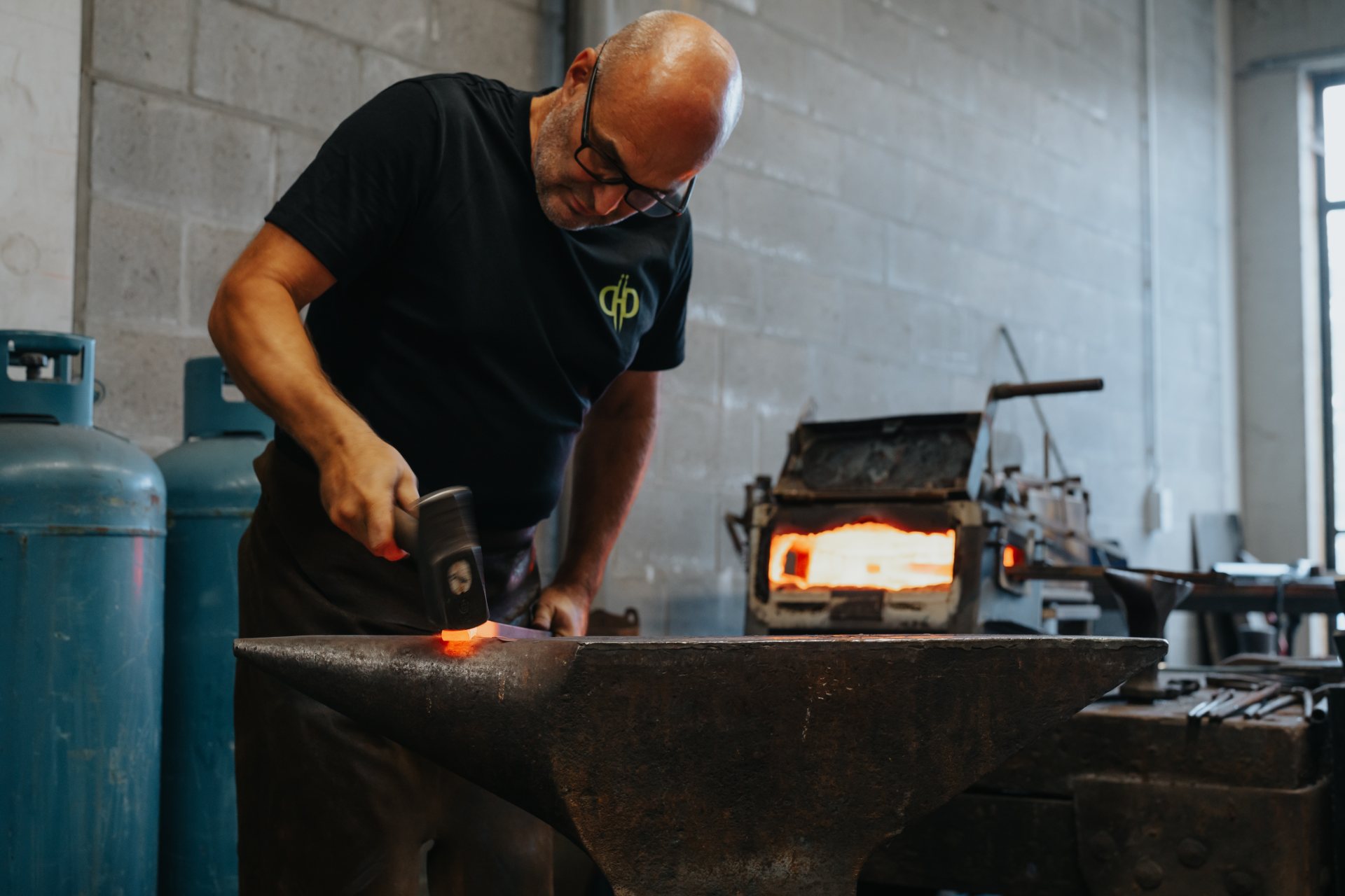Smid van De Nieuwe Smid bewerkt gloeiend staal op het aambeeld in het atelier in Lier