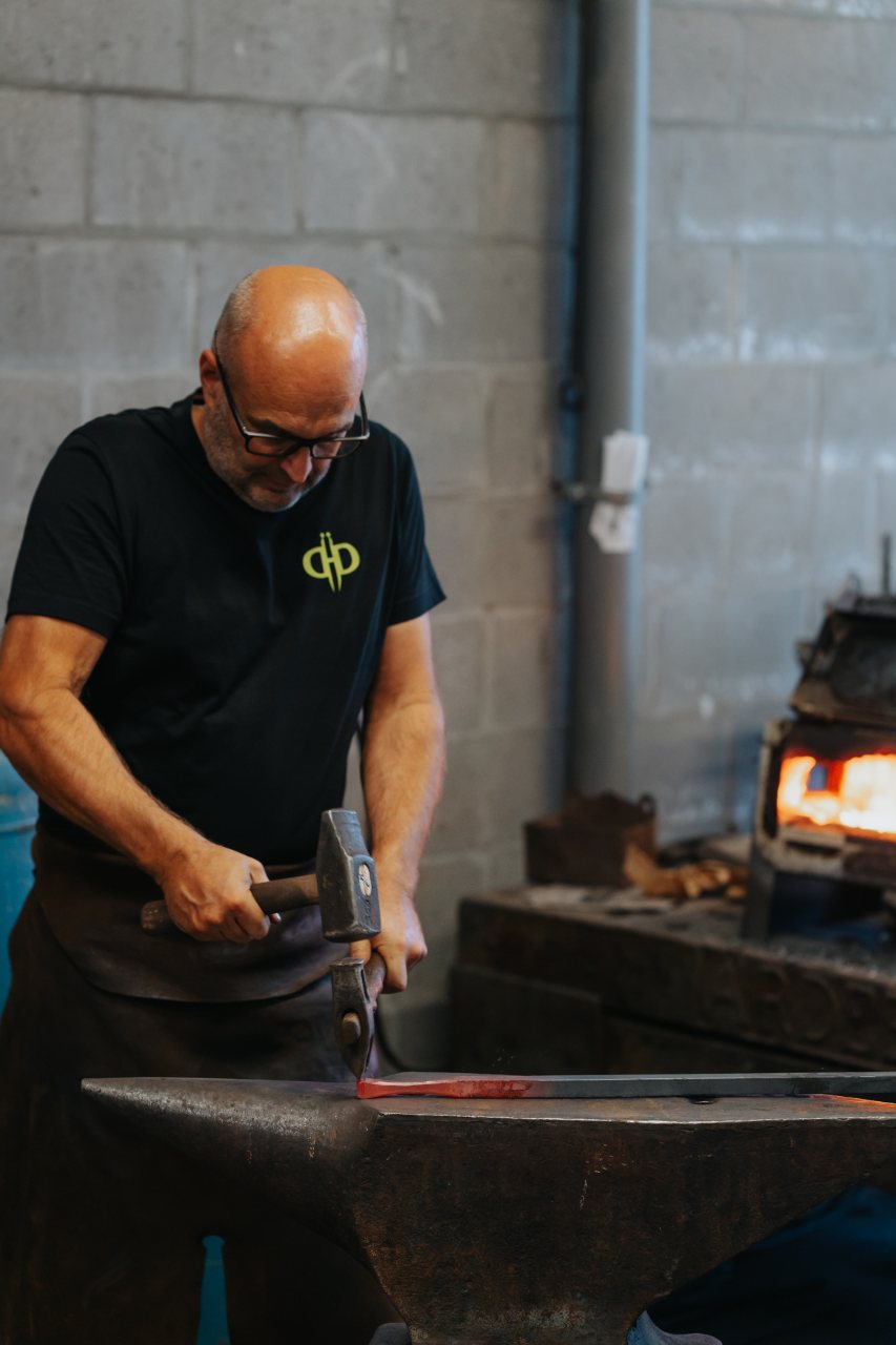 Smid van De Nieuwe Smid smeedt staal op het aambeeld in het atelier in Lier